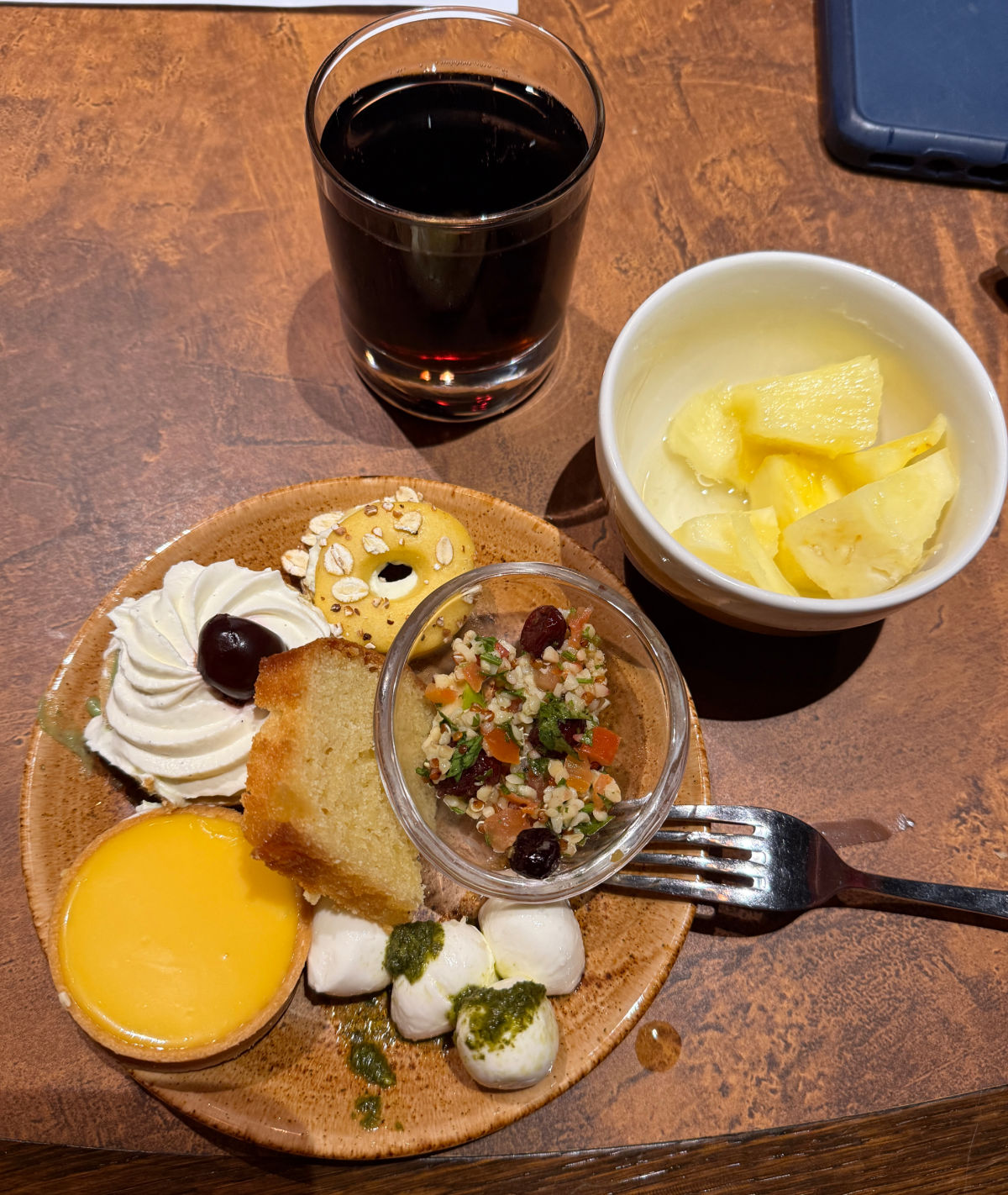 A plate of pastries and snacks next to a bowl of pineapple.